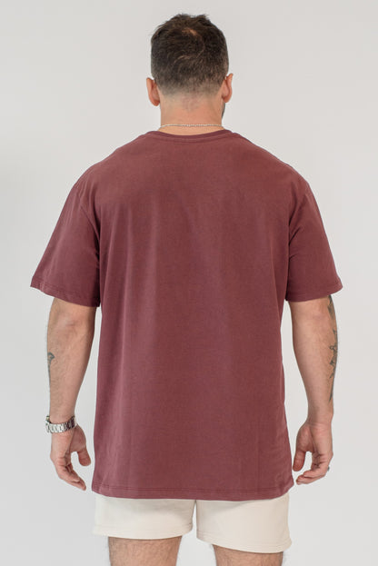 Man wearing a maroon t-shirt and beige shorts on a white background
