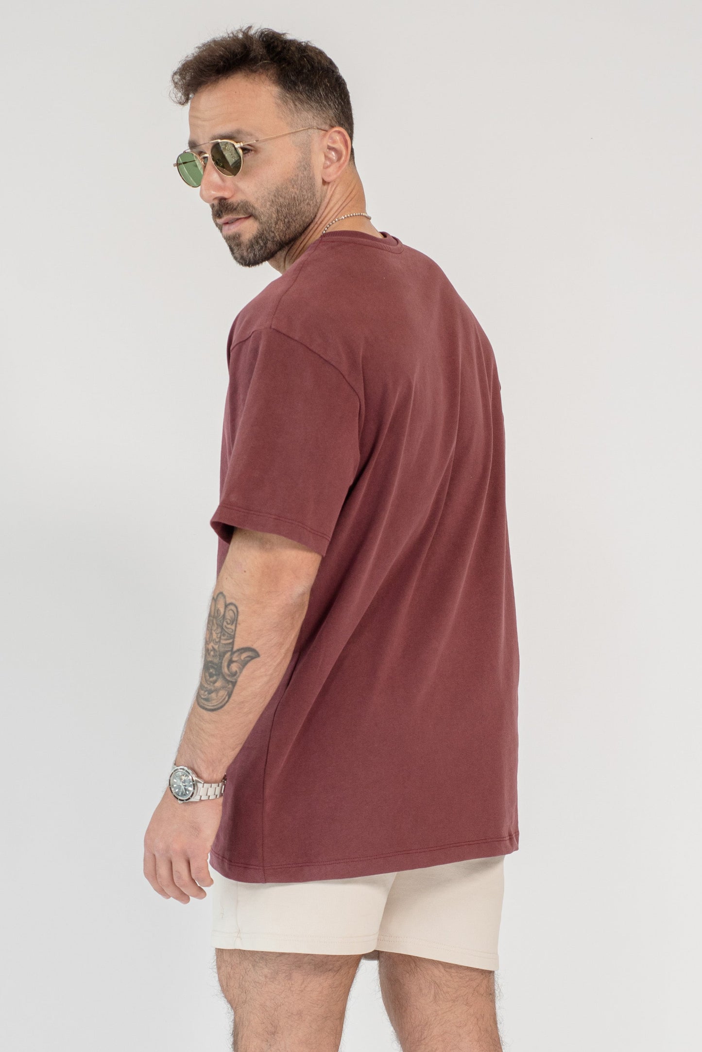 Man wearing a brown t-shirt and beige shorts on a white background