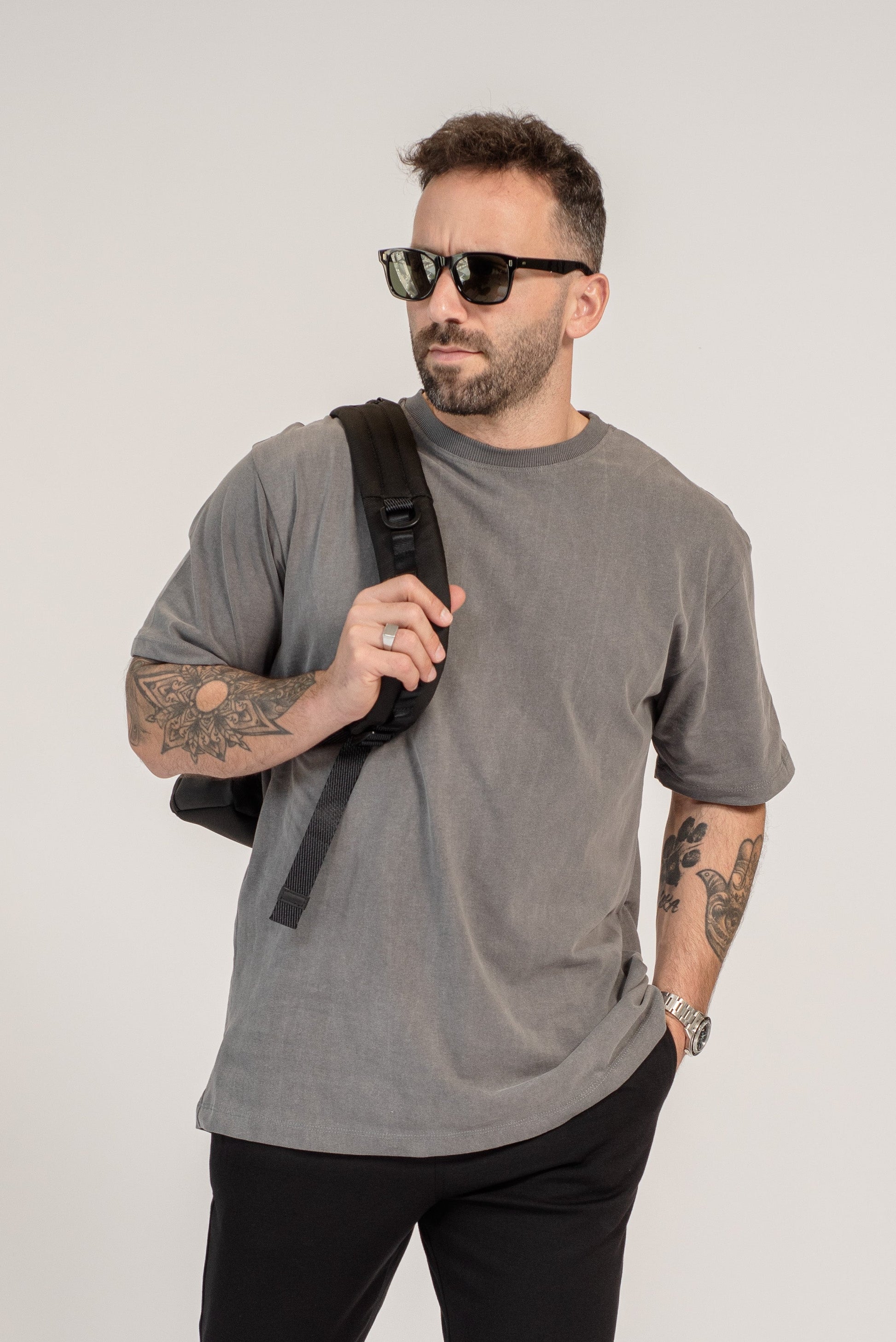 Man wearing a gray t-shirt, black pants, and sunglasses on a white background